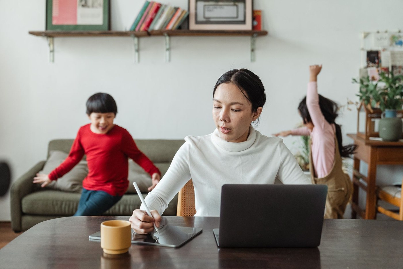 自宅のテーブルで作業する親と遊ぶ子どもたち