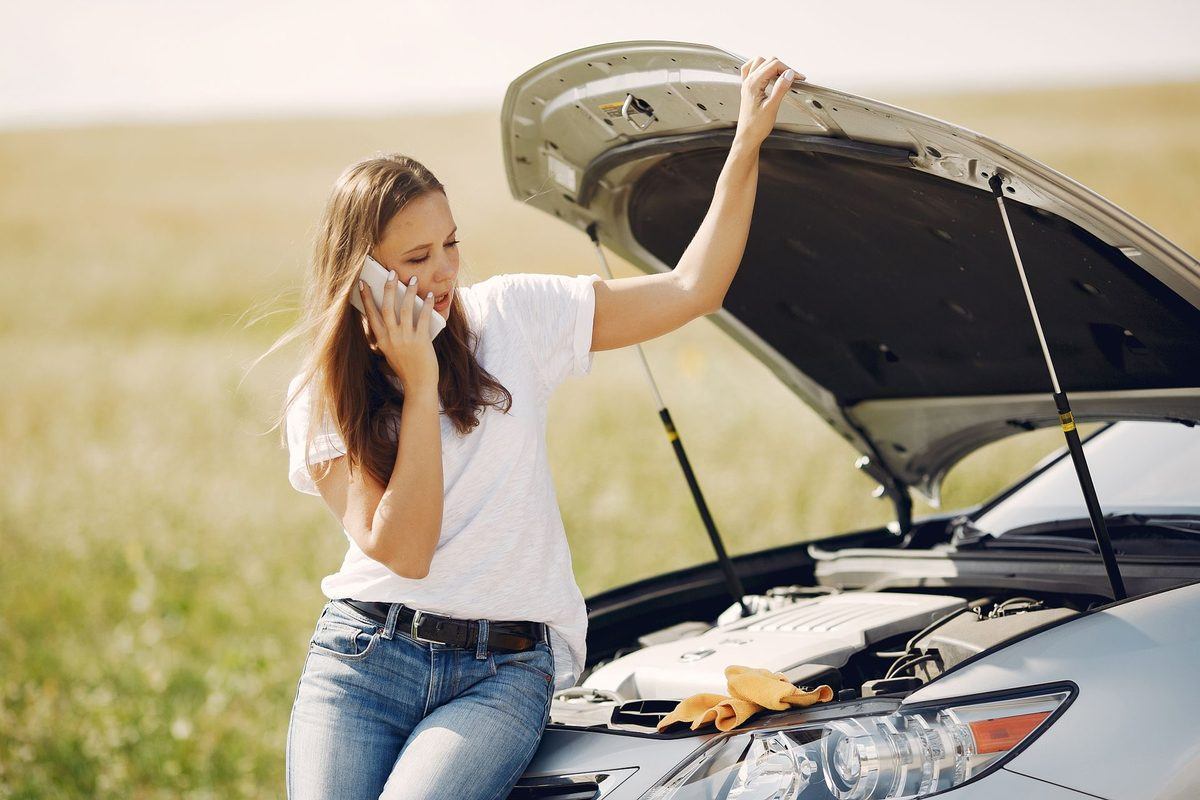 止まった車のそばで電話をする女性